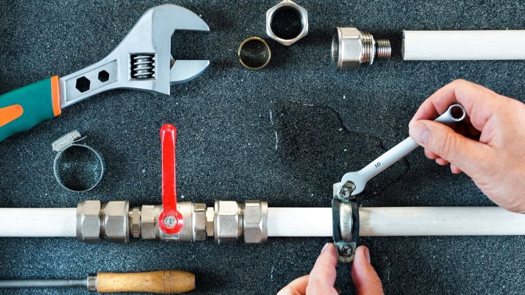 Plumber repairing a pipe valve with an adjustable wrench in Rialto