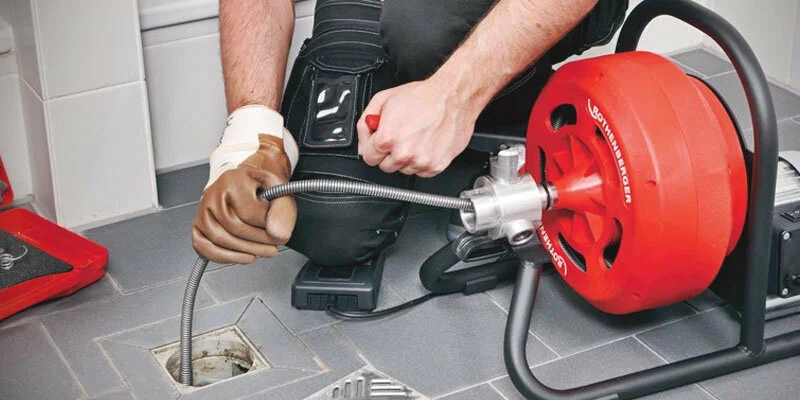 Plumber using a drain-cleaning machine in Rialto