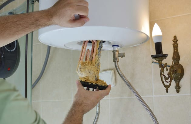 Technician removing mineral buildup from a water heater in Rialto