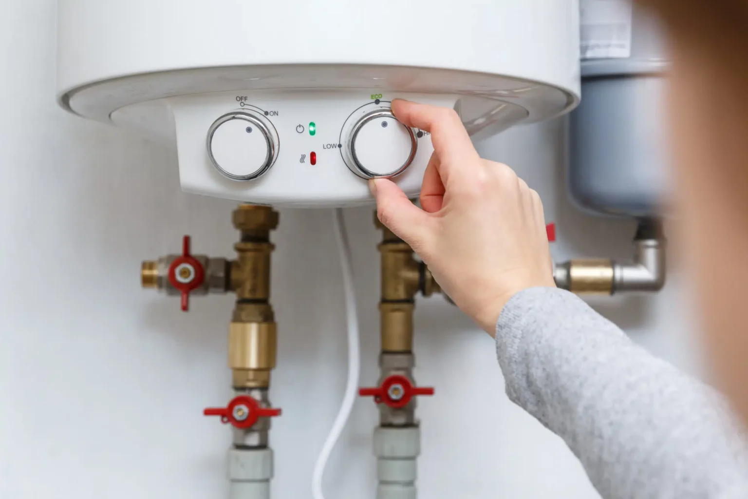 Homeowner adjusting the temperature controls on a water heater in Rialto
